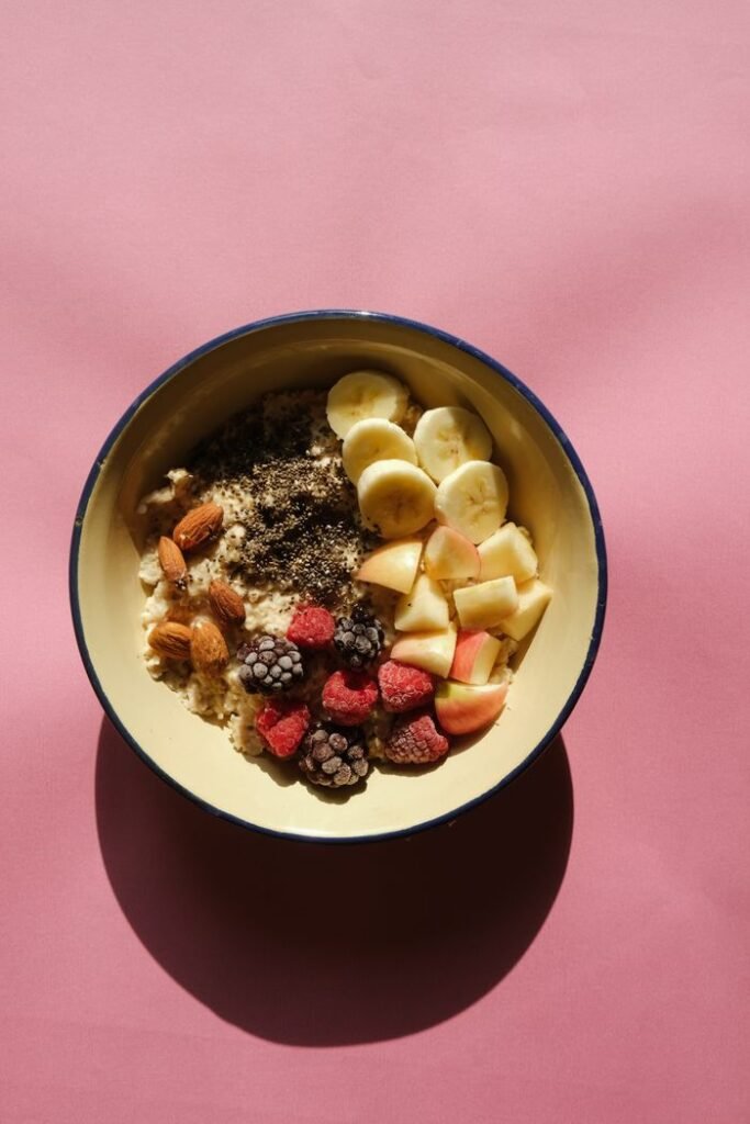 Delicious breakfast bowl with fruits, nuts, and oats on pink backdrop.