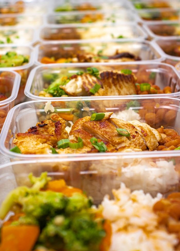 Colorful meal prep containers with grilled chicken, rice, and vegetables neatly packed.