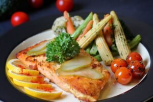 A beautifully plated salmon dish with fresh vegetables and lemon slices, perfect for a gourmet meal.